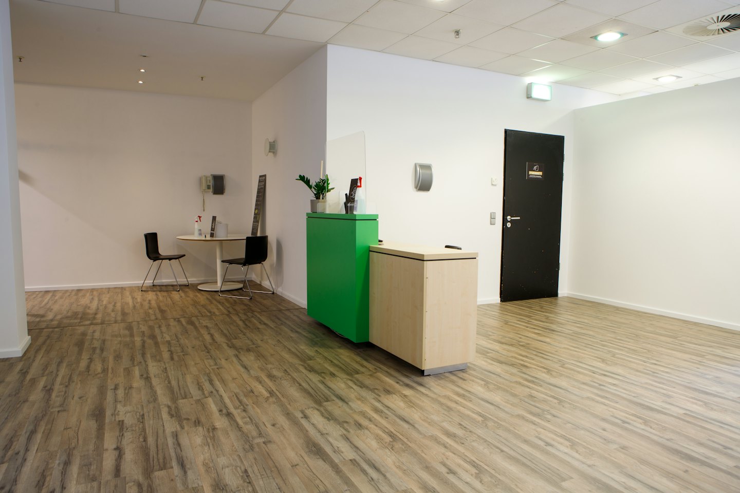 Moderne Bürolobby mit grünem Empfangstresen und Sitzgelegenheiten.