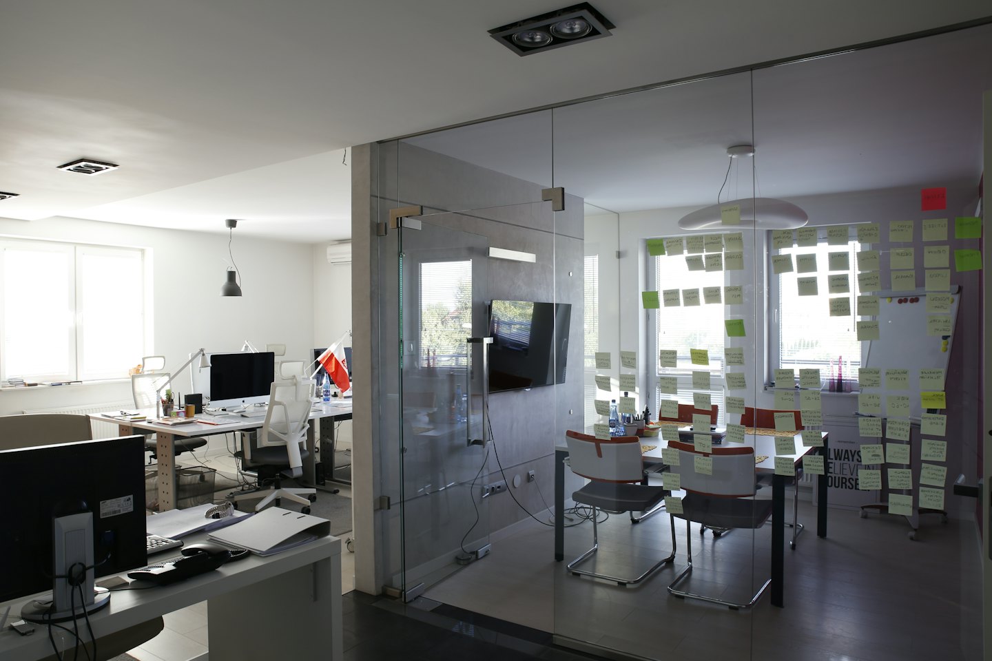Modernes Büro mit einem Besprechungsraum voller gelber und grüner Haftnotizen.