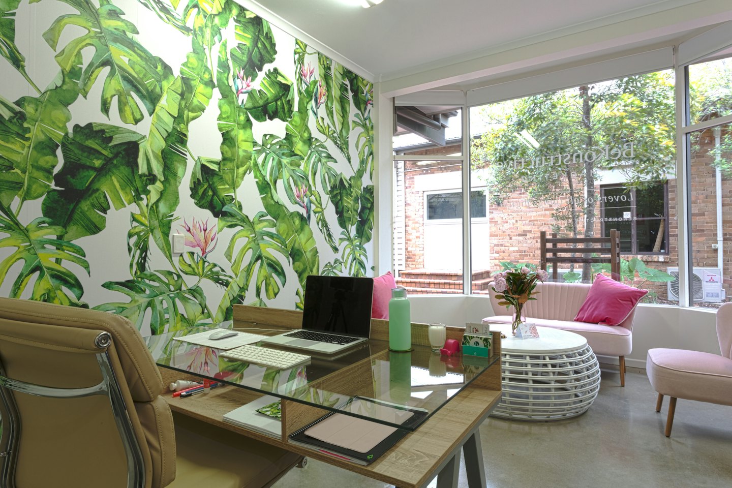 Modernes Büro mit Holztisch und floraler Wandmalerei.